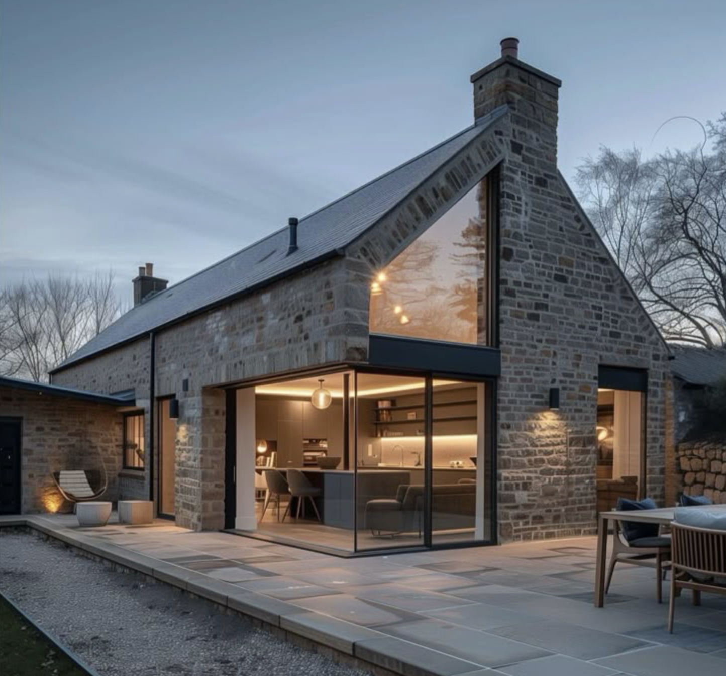 Modern stone house with large glass windows, outdoor patio, and minimalistic furniture.