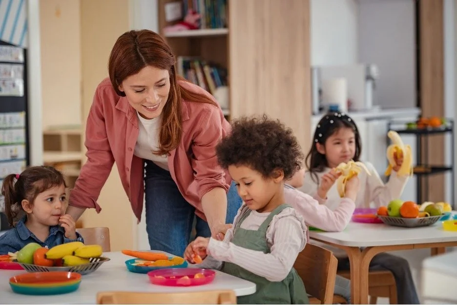 A corporate childcare nanny helping kids at lunch.