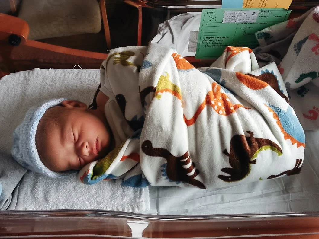 Photo of a swaddled baby in a hospital bassinet