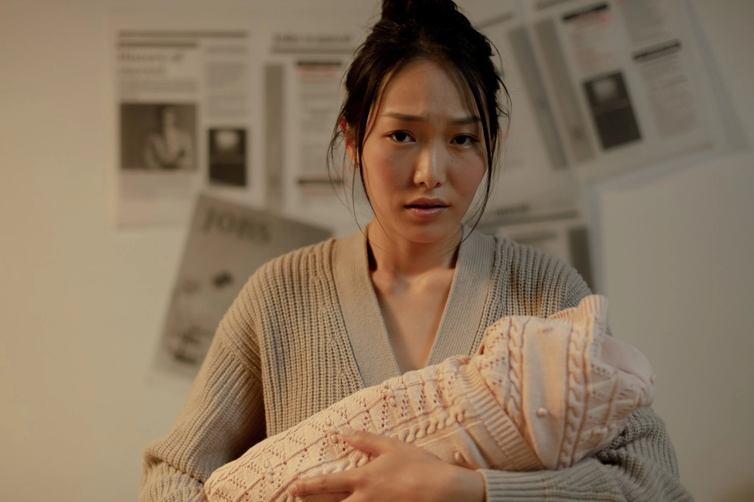 New parent holding a swaddled newborn and looking overwhelmed, illustrating the emotional impact of perinatal ADHD and postpartum depression risk.