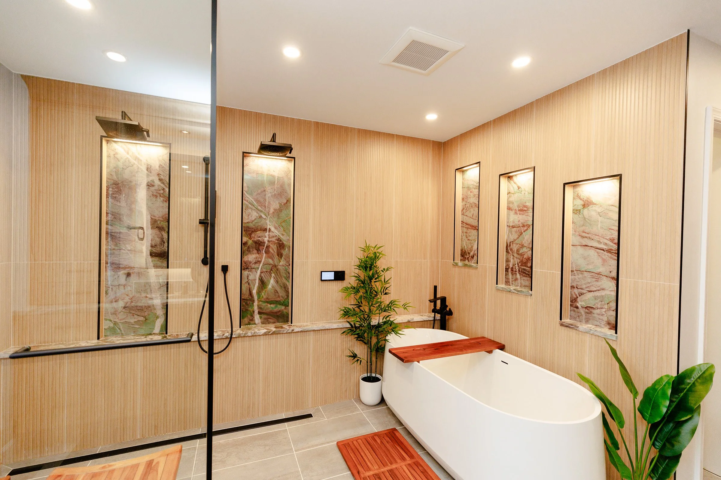 Modern bathroom with a walk-in shower, a bathtub, and decorative wall panels. Includes green plants and wooden accents.