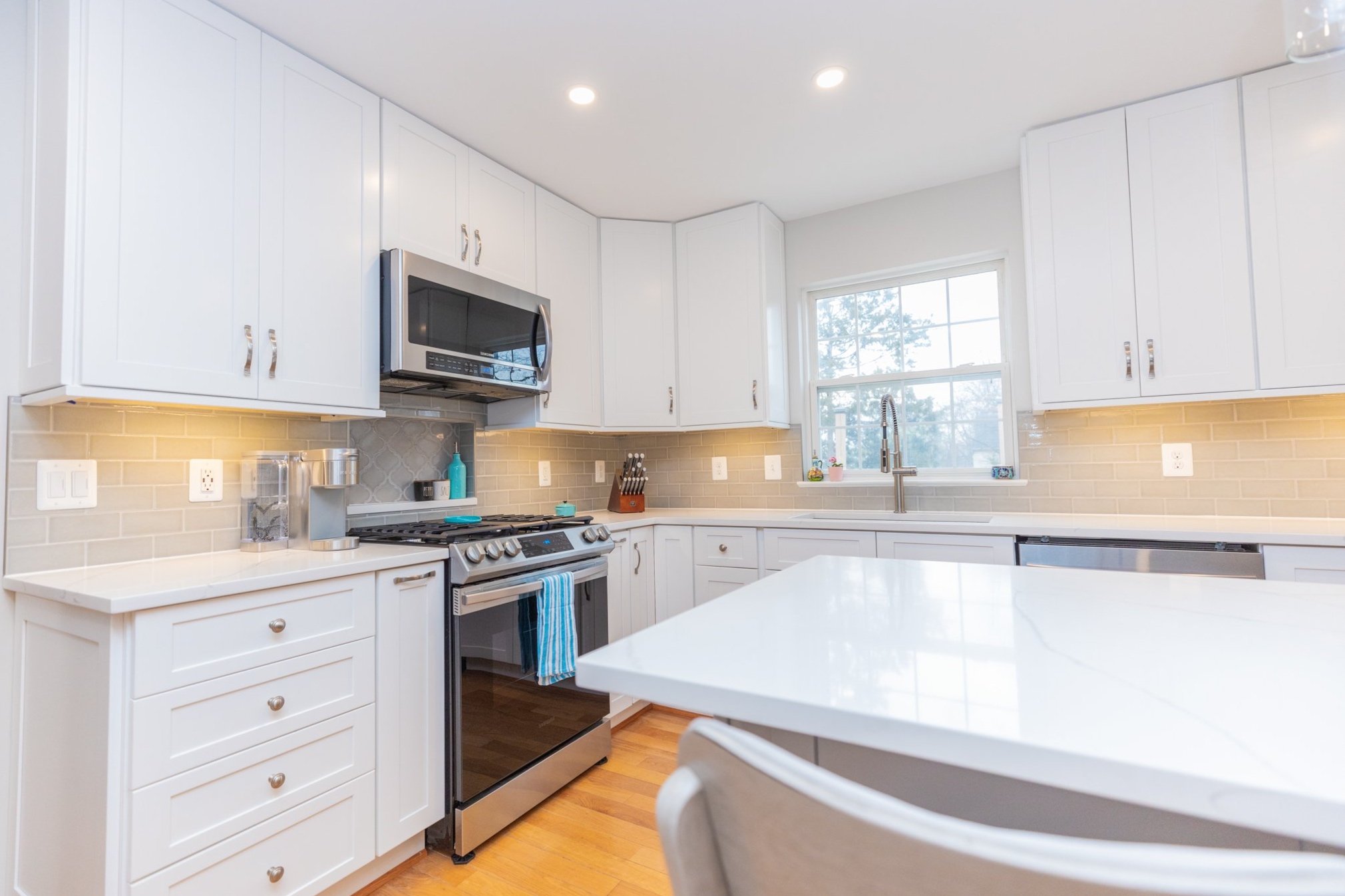 Modern kitchen with white cabinets, stainless steel appliances, granite countertops, and a large window.