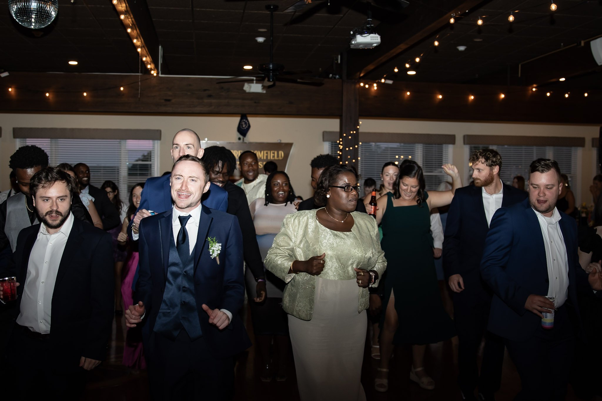 People dancing and celebrating at an indoor wedding reception or party.