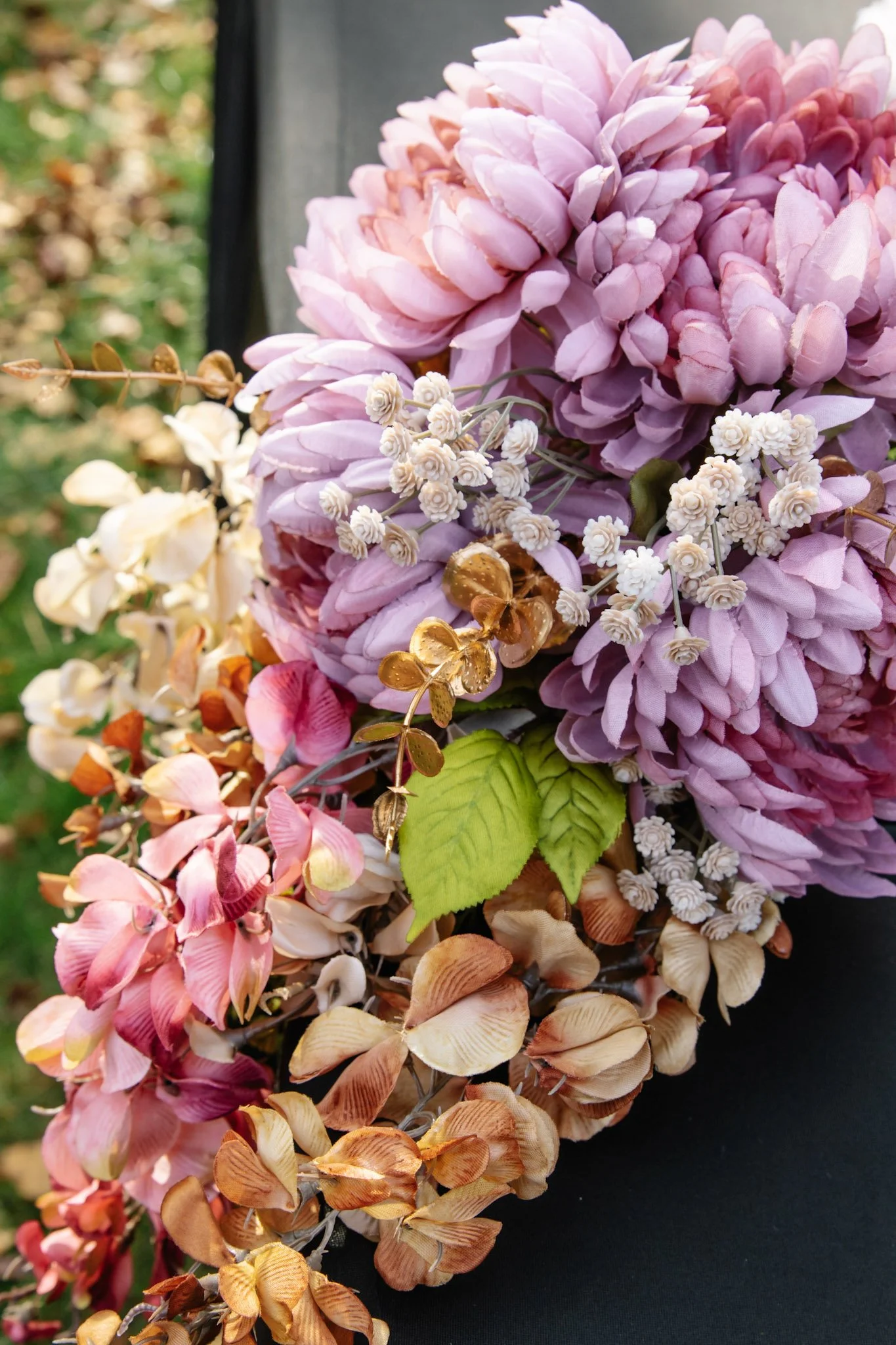 Close-up of a colorful floral arrangement with pink, white, purple, and orange flowers, including hydrangeas, orchids, and other decorative blooms.
