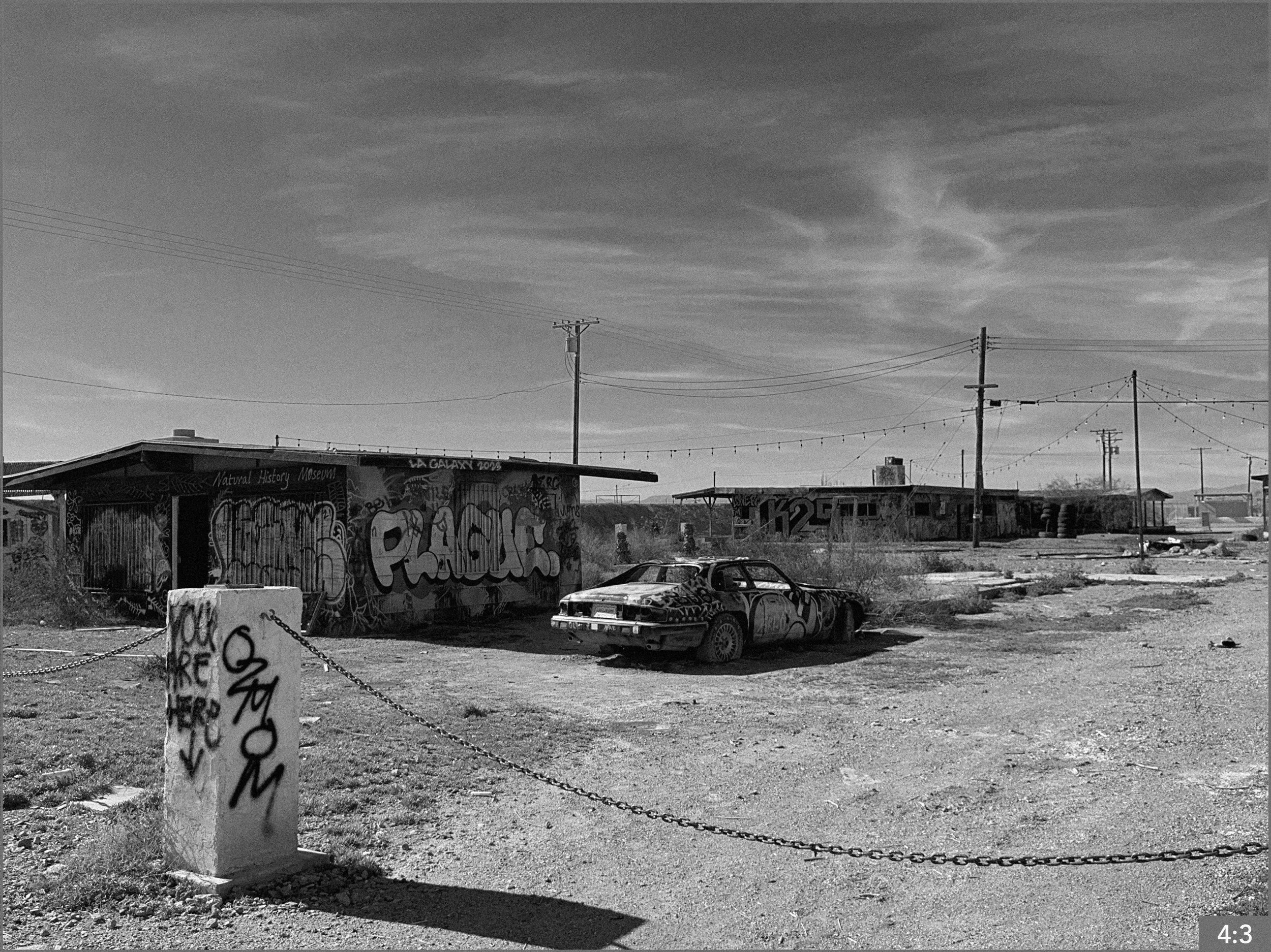 19. Bombay Beach Salton Sea 11:00 am 2. SHOT LONG MEDIUM CLOSE: Daughter stands in a doorway of an abandoned shack.
