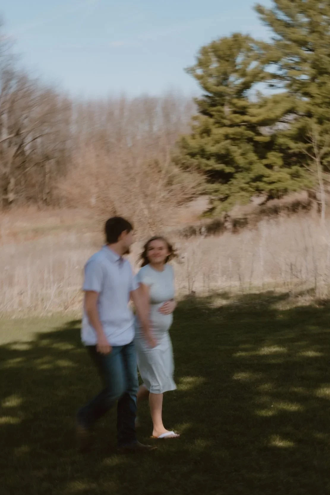 couple walking together in park during maternity session