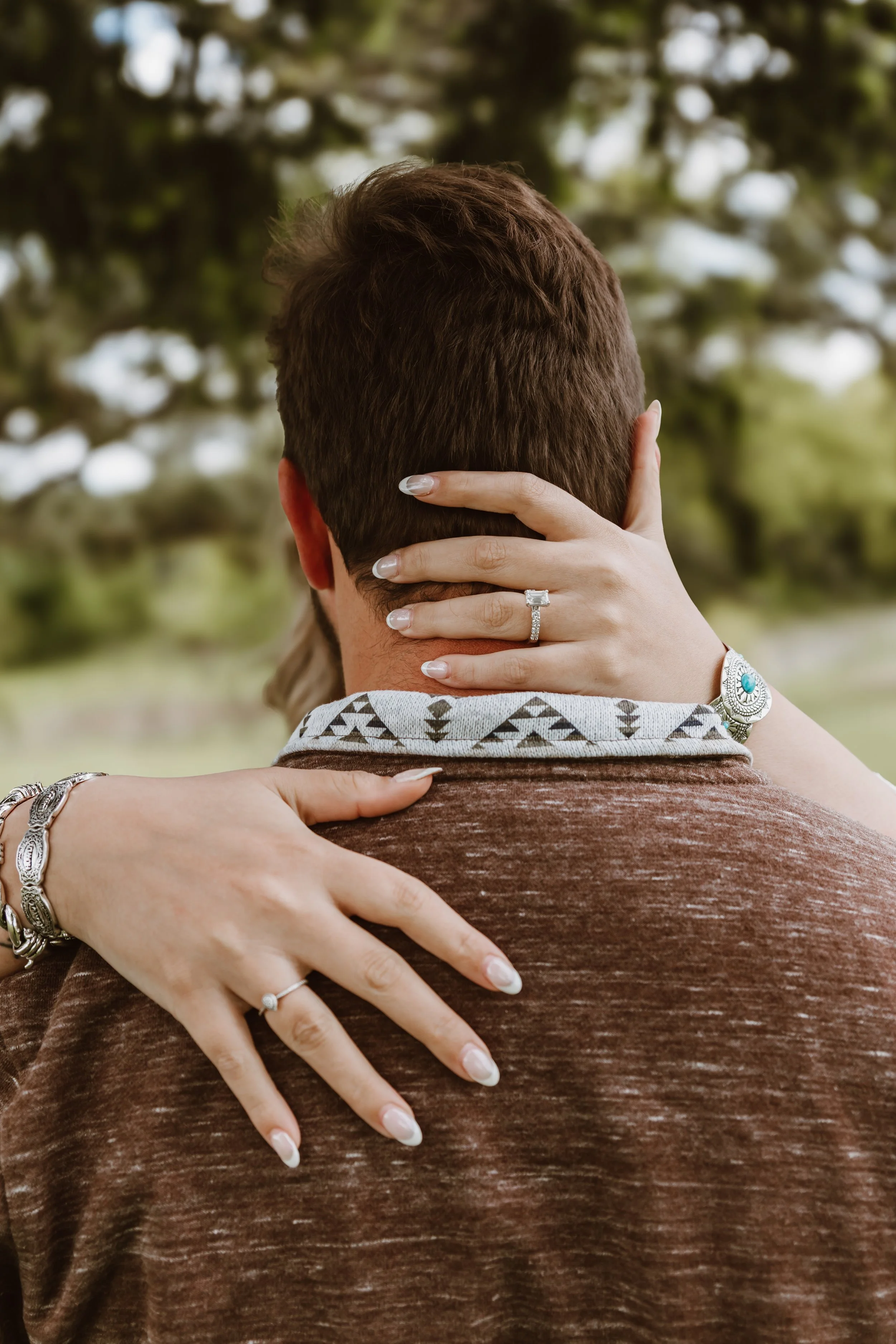 close up of hands showing engagement ring during outdoor spring photo session