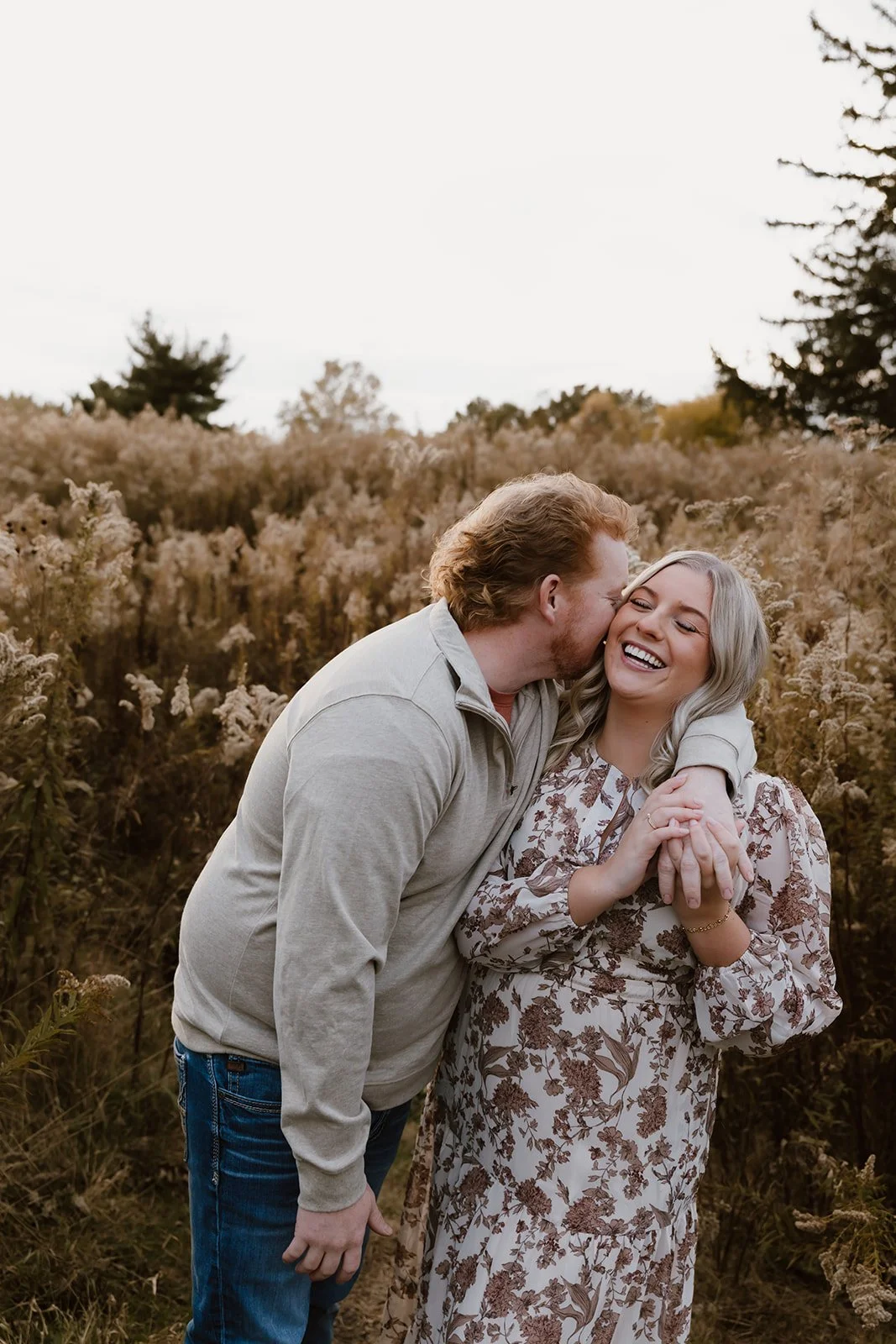 Man kissing woman on the cheek during romantic couples session outdoors