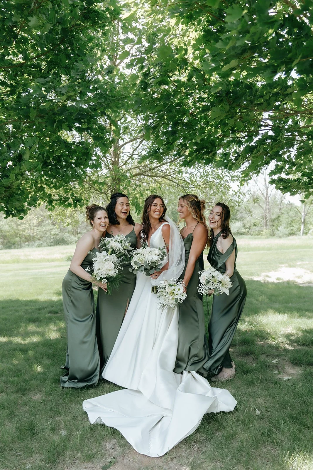spring wedding in Central Illinois with award winning photographer showing bride and bridesmaids posing under beautiful greenery