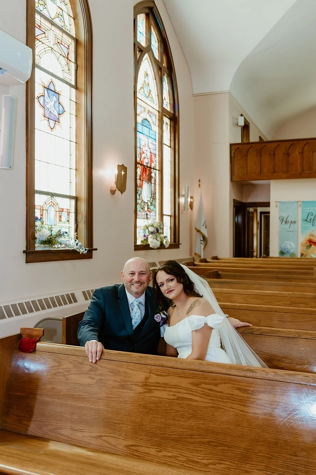 bride and groom sitting in a pew