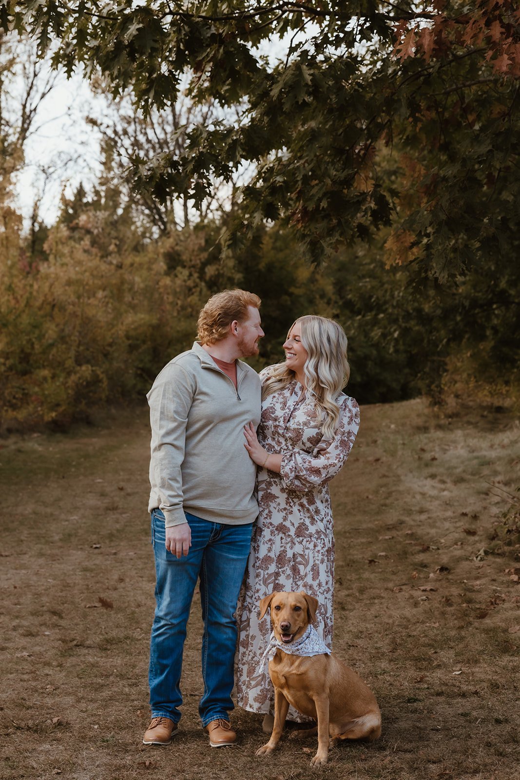 Couple walking a wooded path with their dog during fall photography session