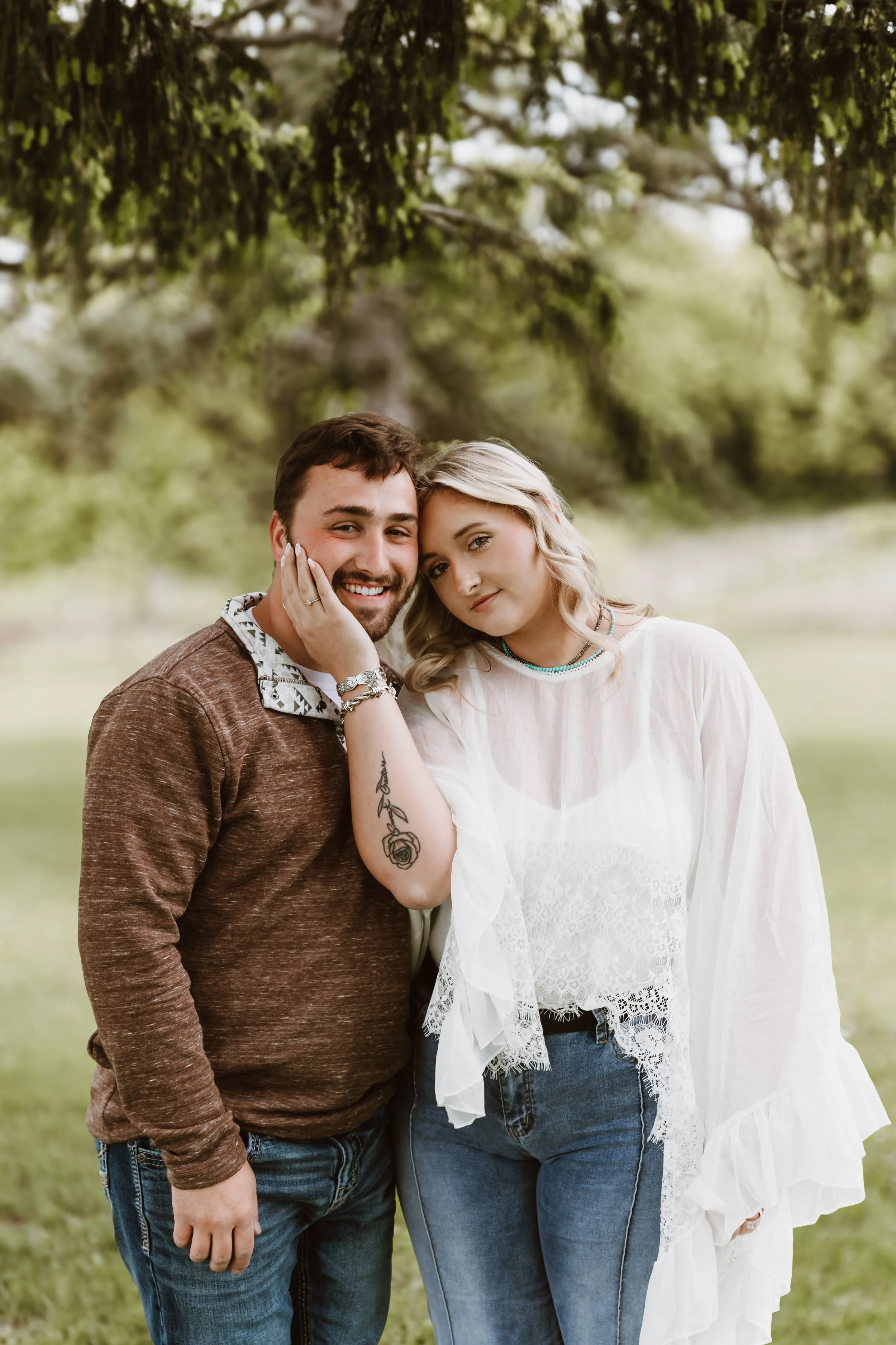 romantic portrait of couple with woman resting head on partner in green outdoor location