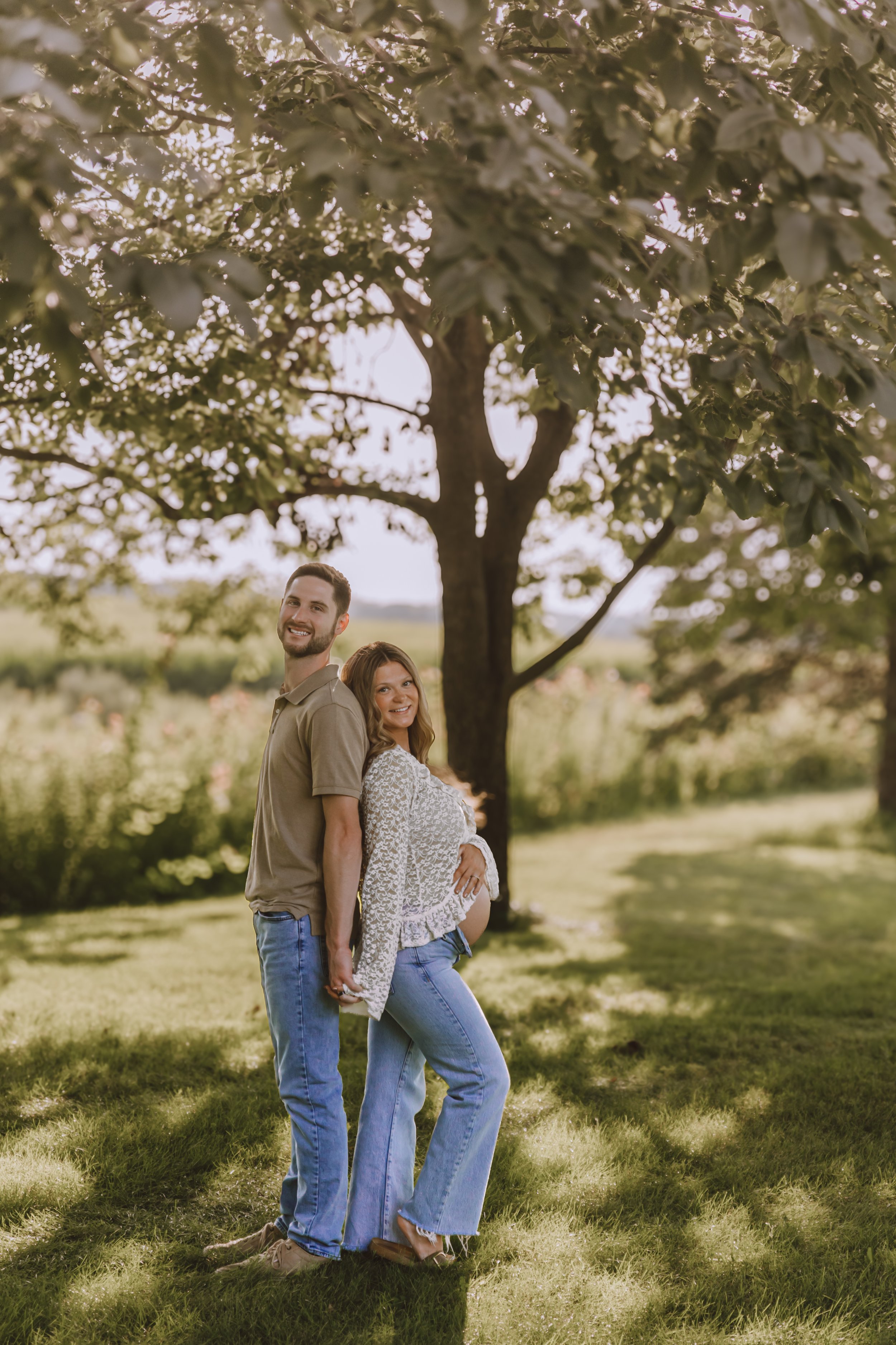 Outdoor maternity portrait of an expecting couple surrounded by summer greenery in Central Illinois.