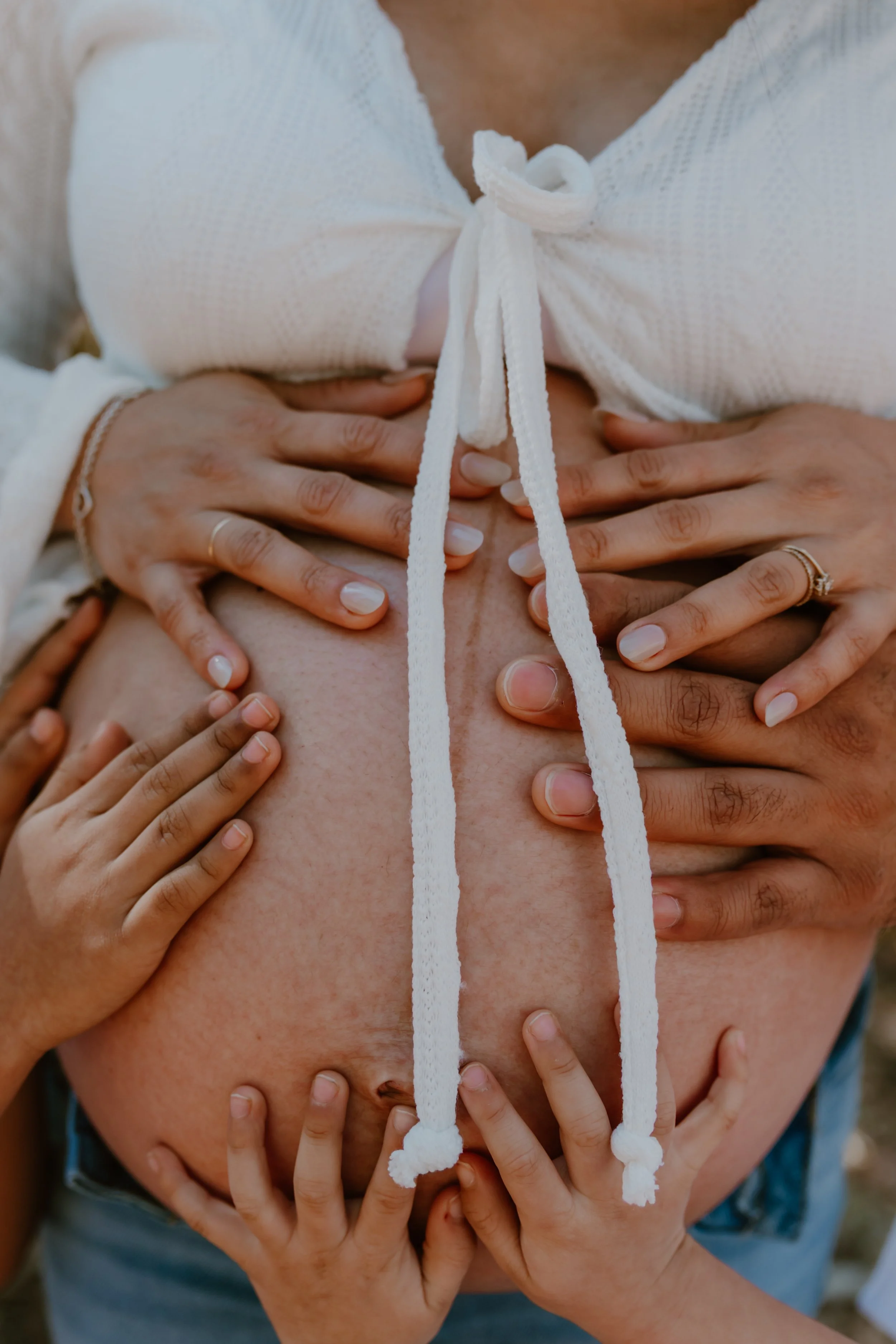 family hands on pregnant belly photo