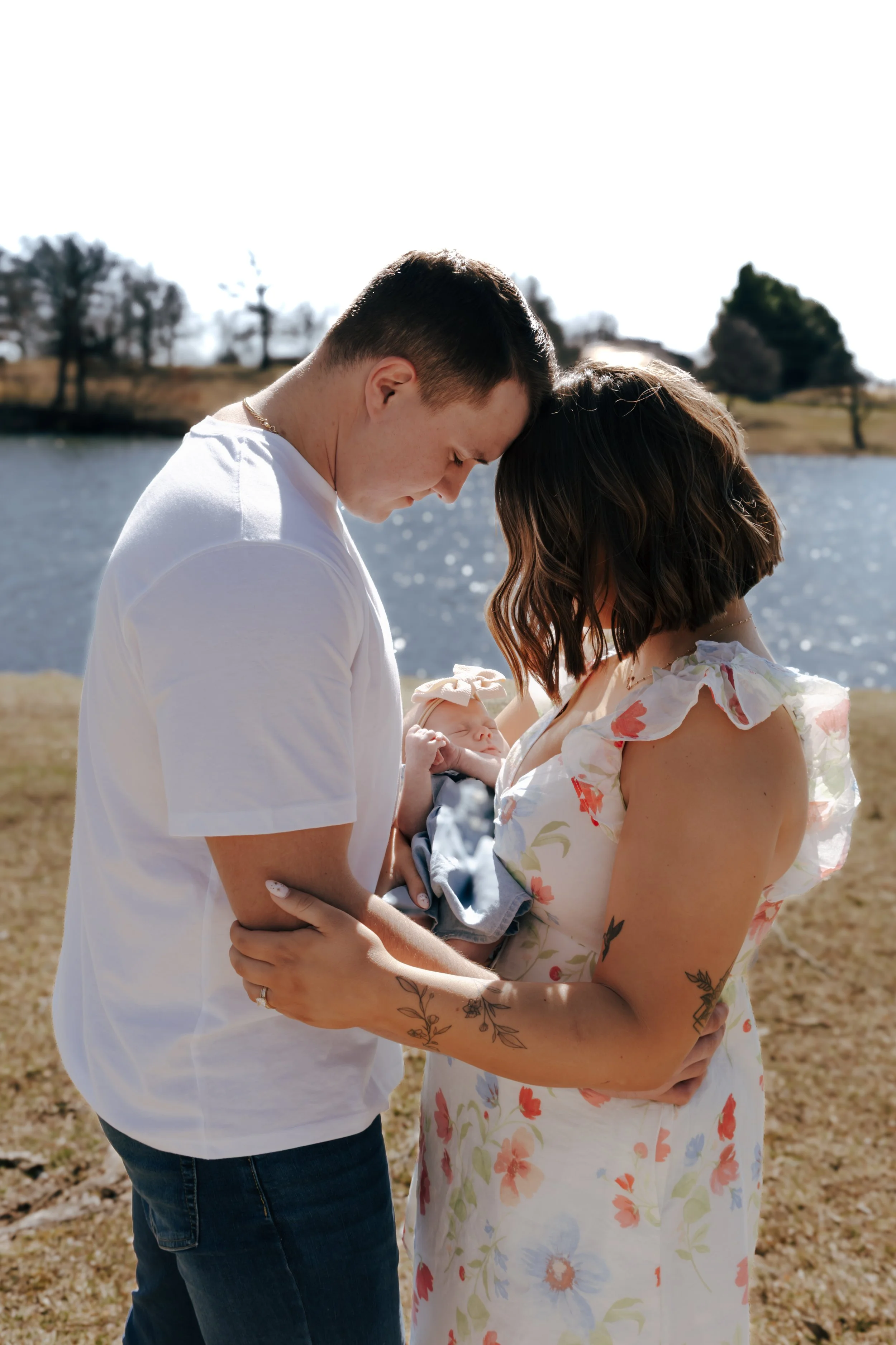 Parents holding newborn together by the lake during family photos in Eureka Illinois