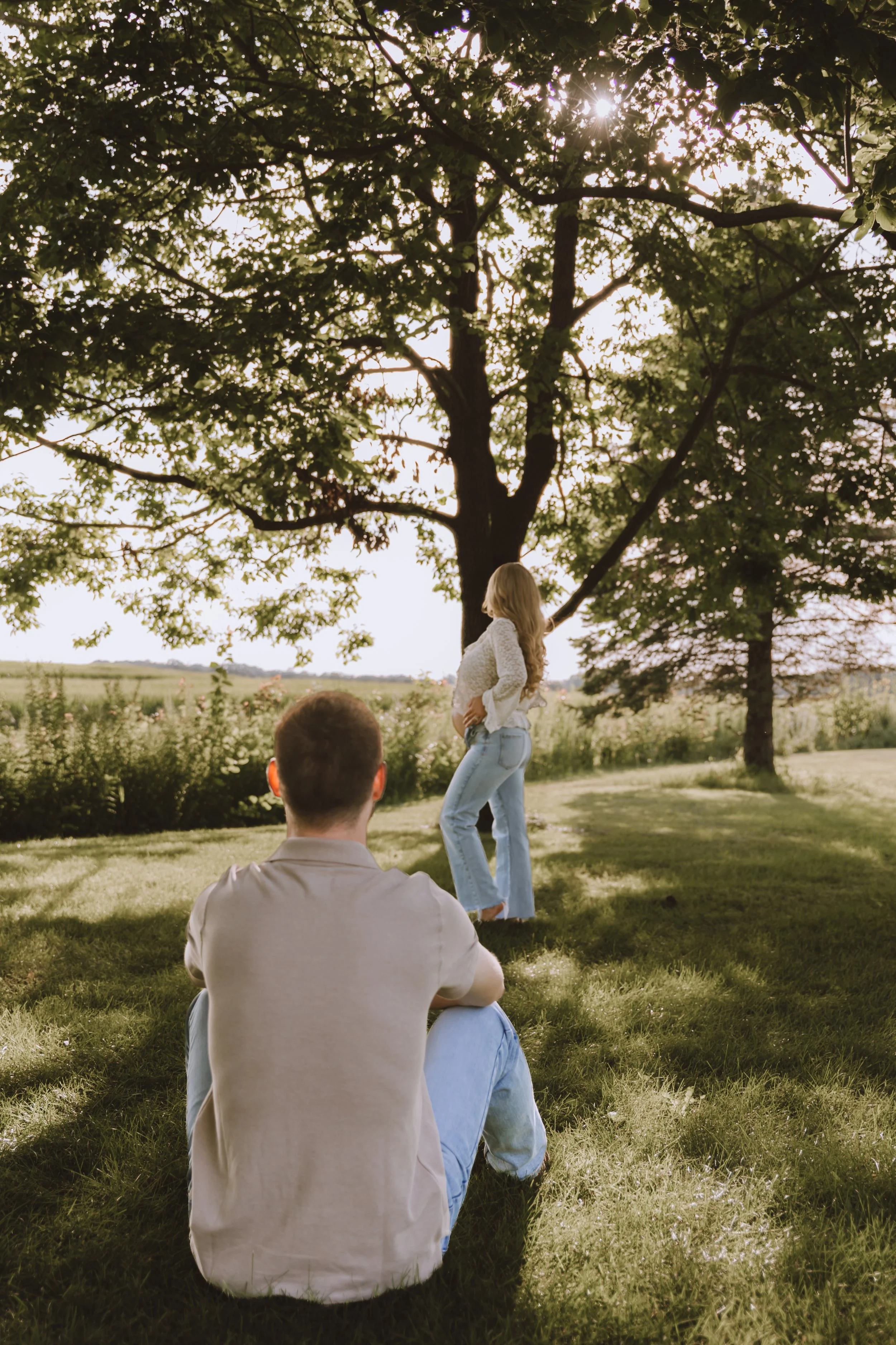 Expecting mother standing beneath trees during a relaxed outdoor maternity photography session in Central Illinois.