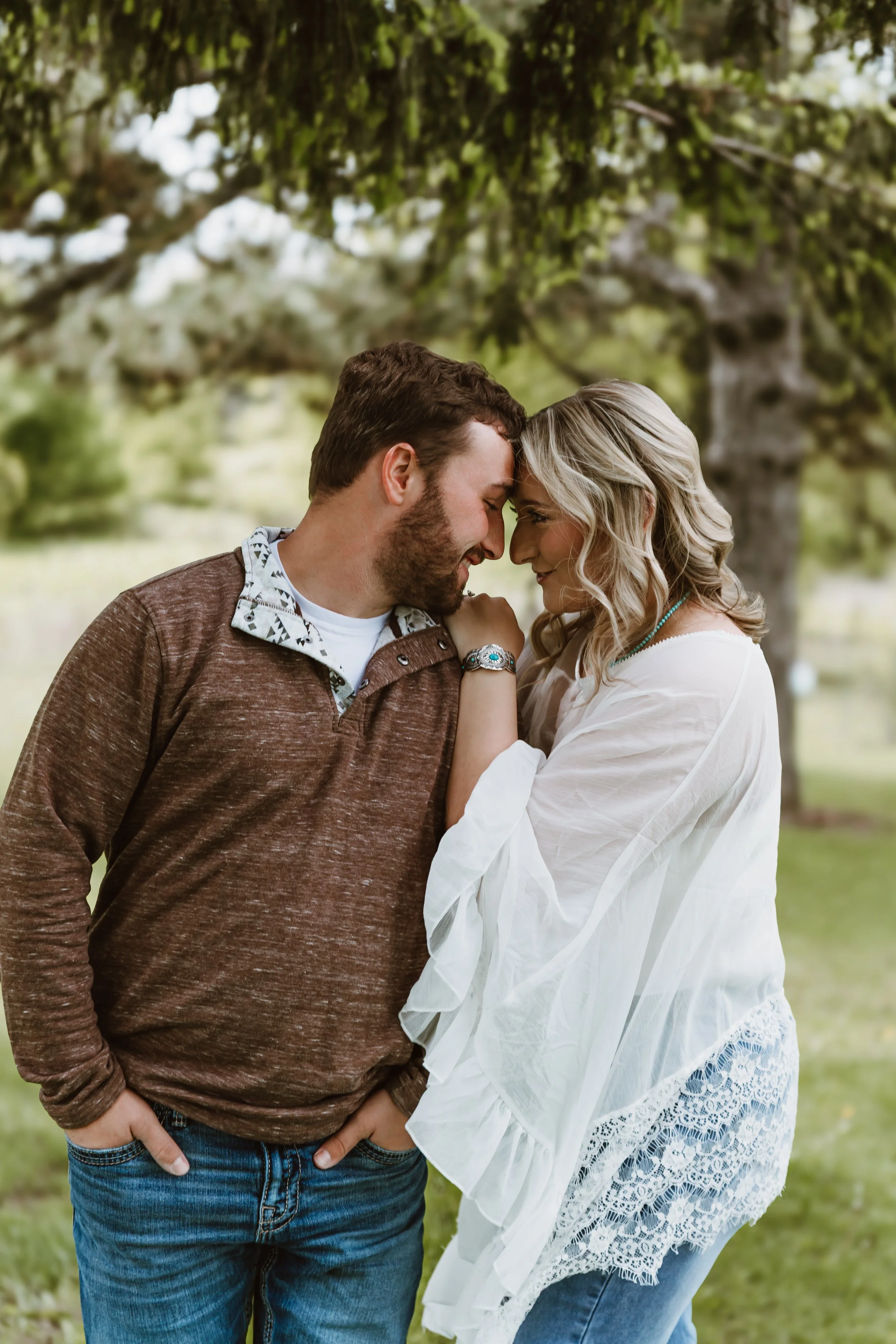 ouple touching foreheads smiling during spring engagement session with soft green background