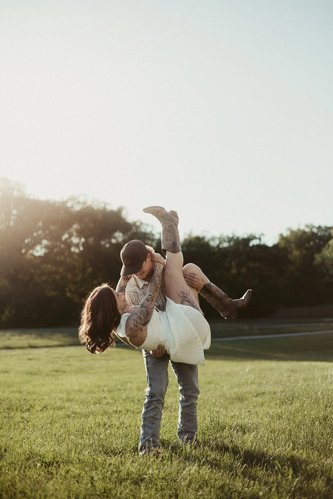 Man lifting woman in sunset field during cinematic couples photography session
