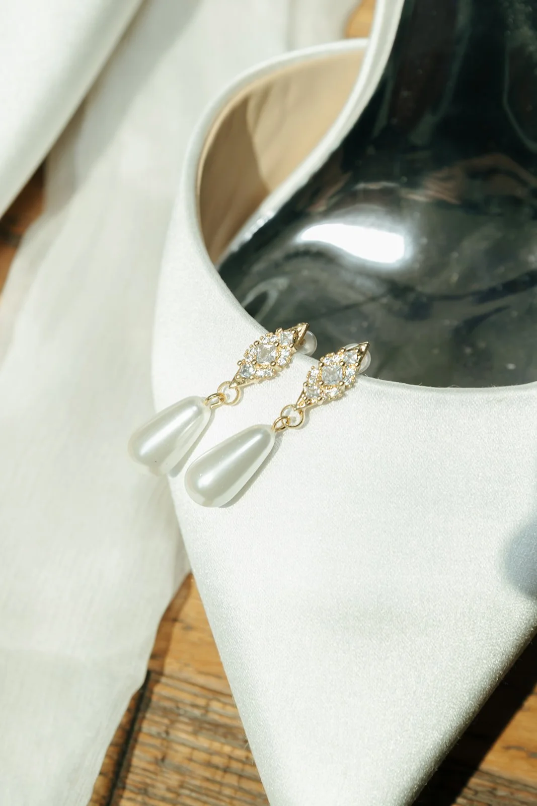 Pearl bridal earrings on satin wedding shoe detail photograph