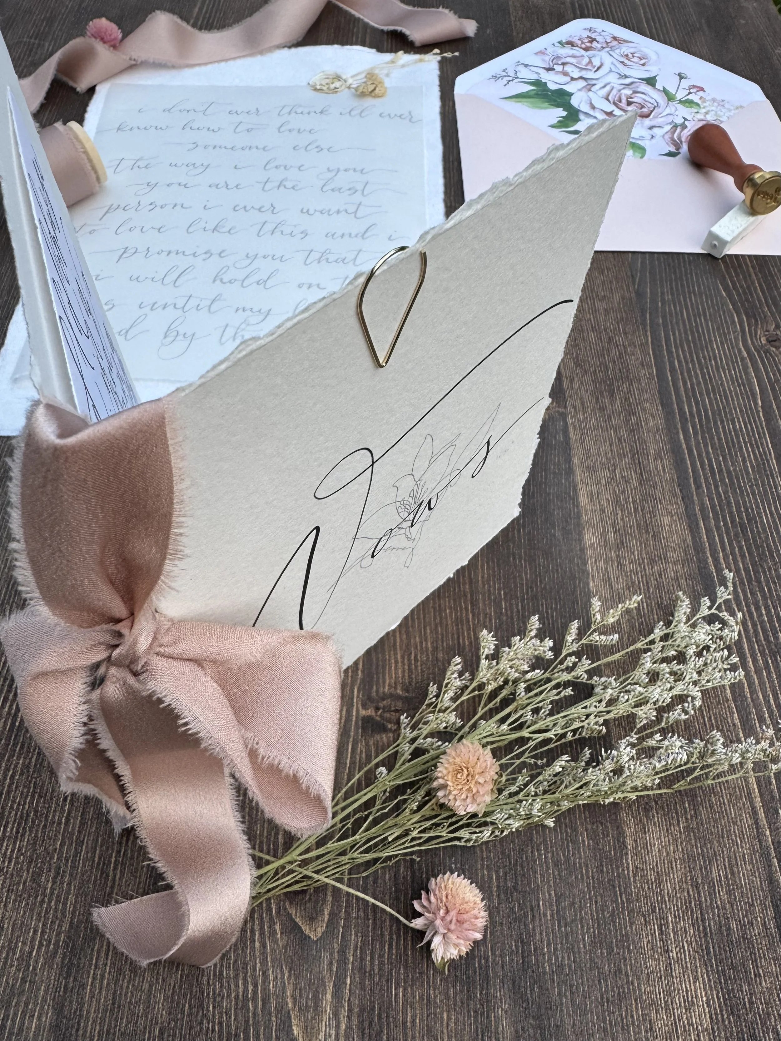 Close up of a vow booklet with a soft blush ribbon for binding