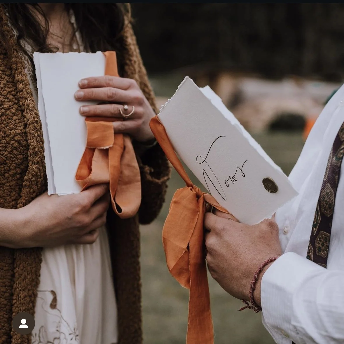 Burnt orange chiffon ribbon binding hand written vows to their beautiful cover. Held in the hands of the people expressing their commitment to one another.