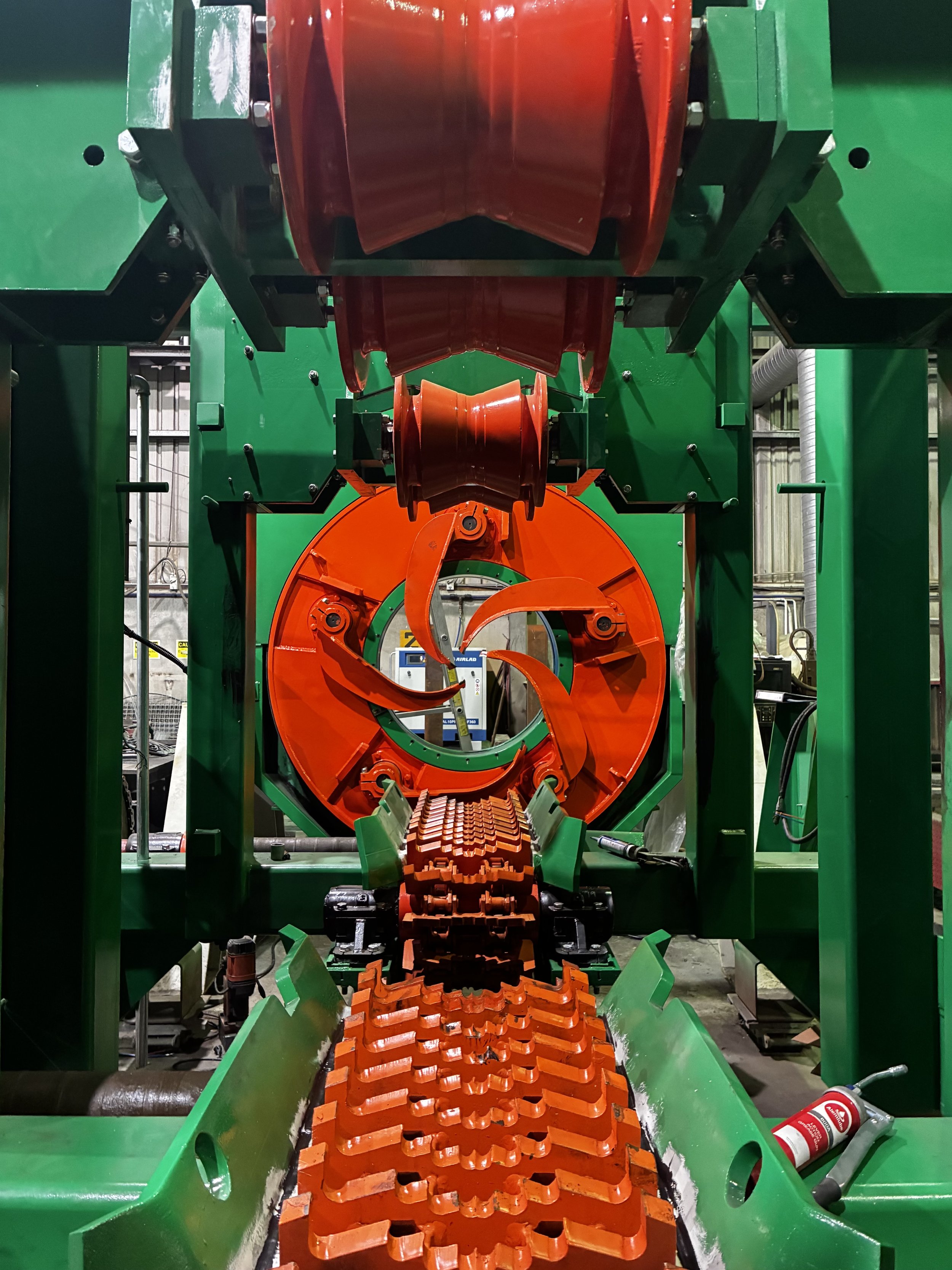 Factory floor with welding equipment and scaffolding under large metal structure.