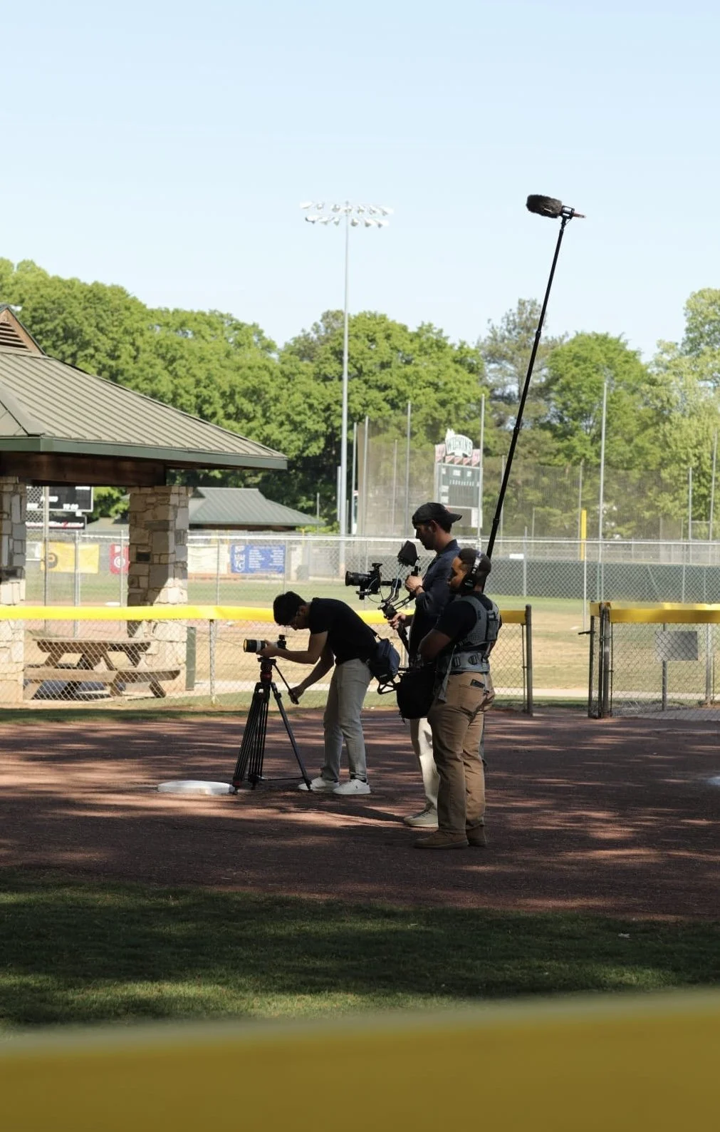 Production crew filming at a baseball field