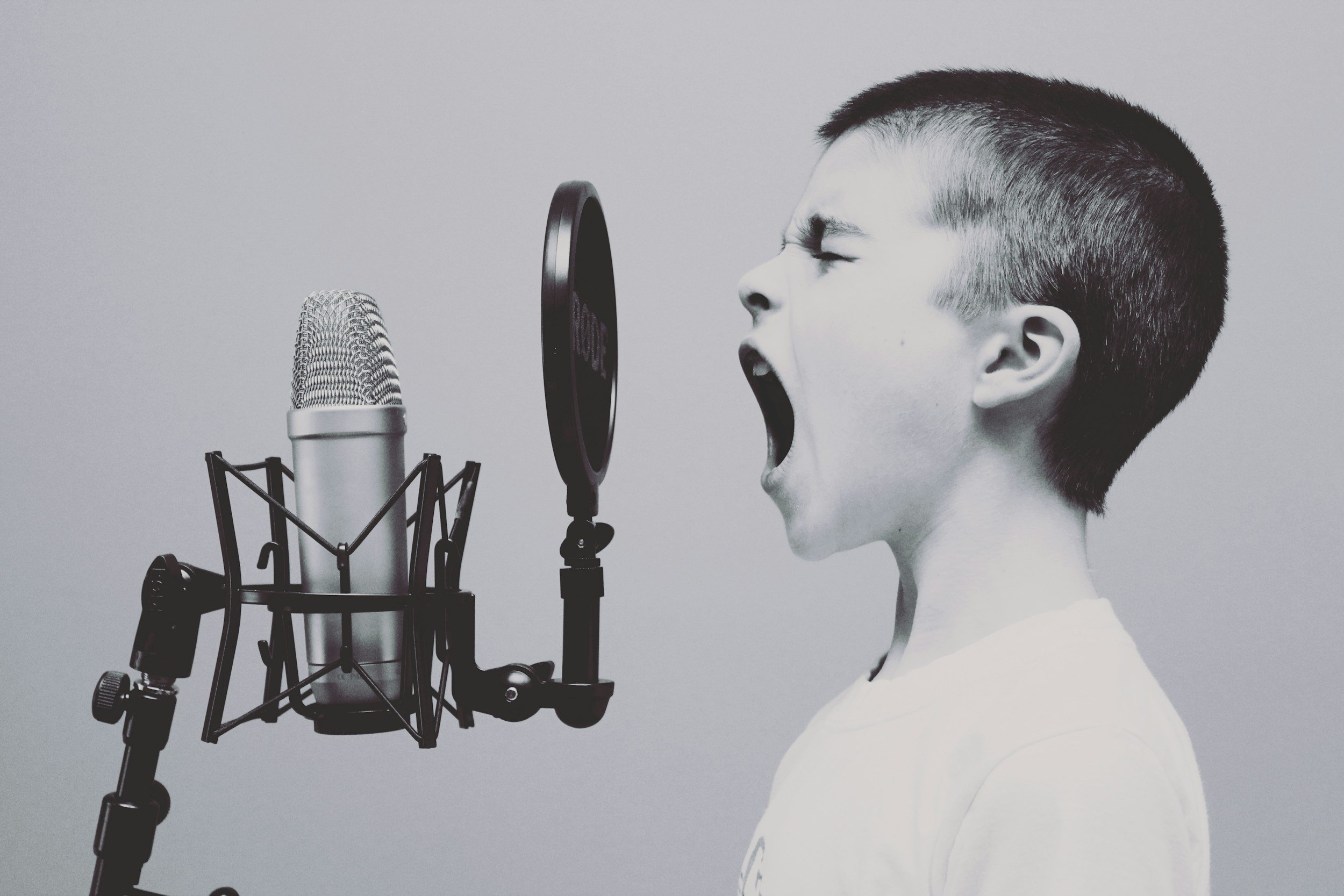 Young boy shouting into an old-time radio microphone.