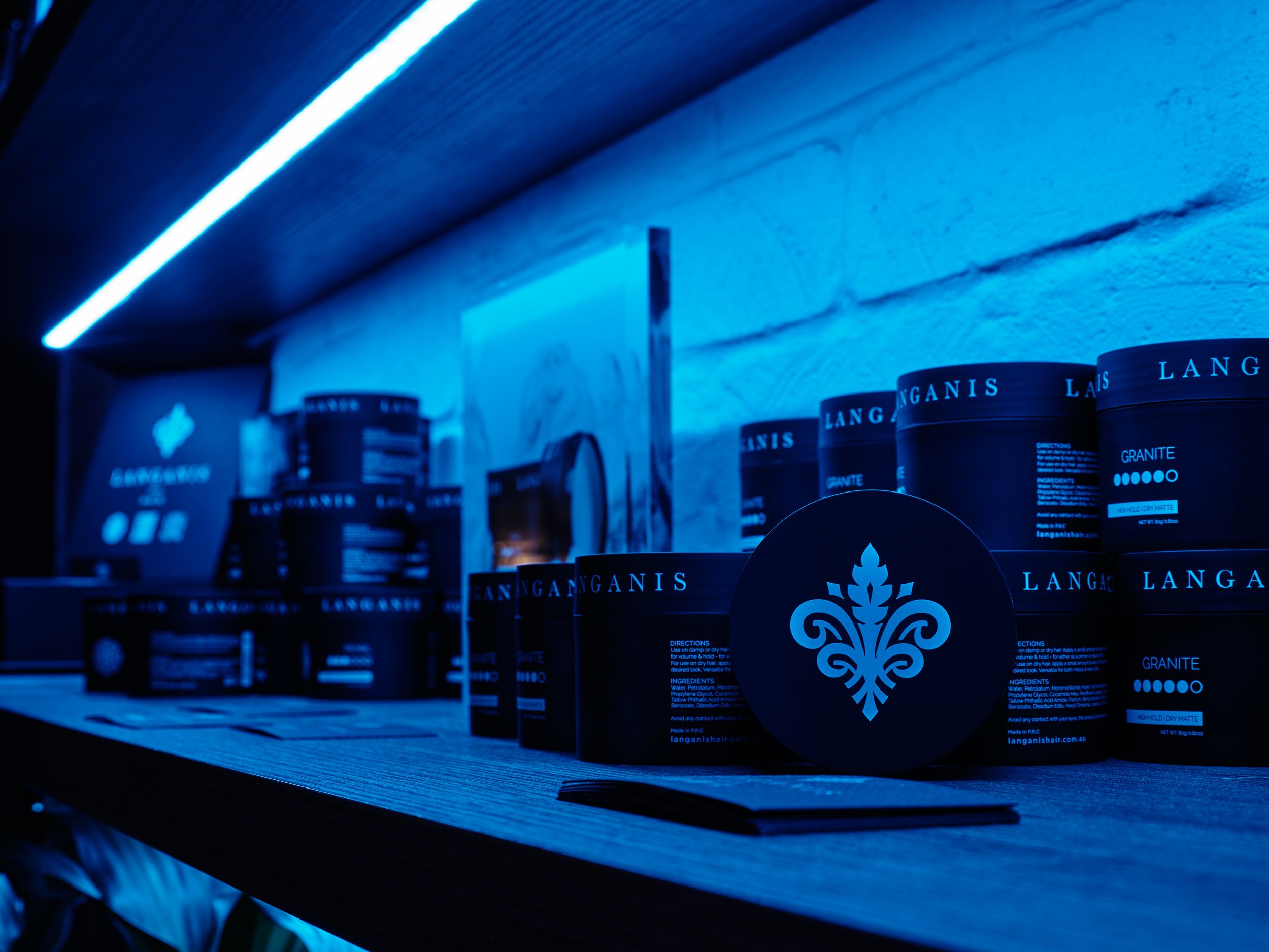 Shelves with black containers labeled 'Langanish' under blue LED lighting.