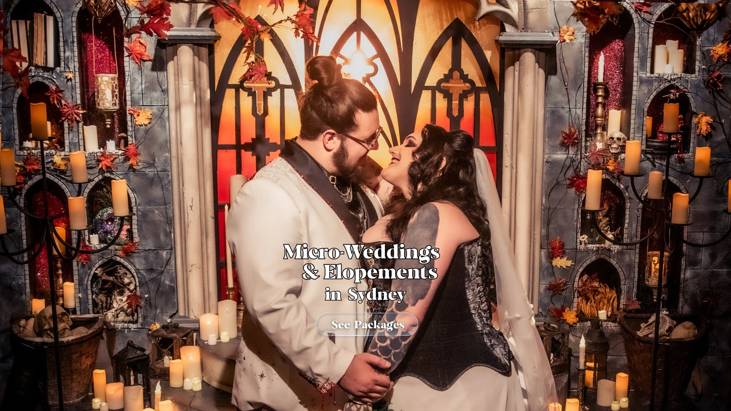 Six adult wedding guests dressed in dark formal attire stand together in a gothic-themed indoor setting decorated with candles, autumn leaves, and arched stone backdrops. Overlaid text reads “Intimate Ceremonies” with a “See Packages” button.