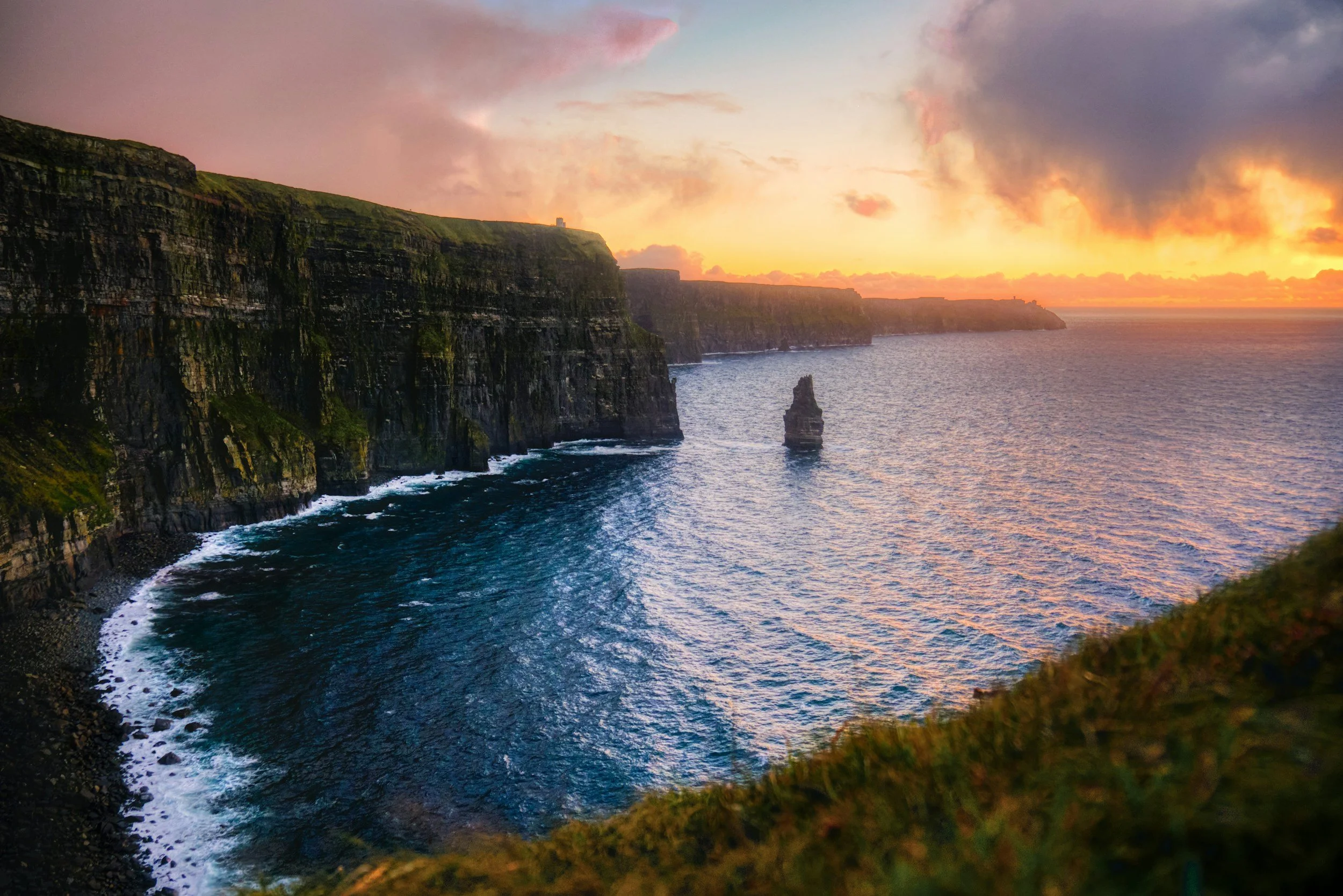 Scenic view of the Cliffs of Moher during sunset, with sea stacks and a colorful sky in Ireland.