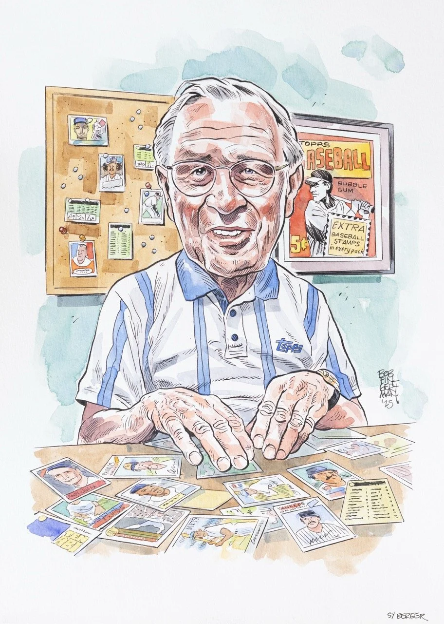 An elderly man with glasses and gray hair, wearing a baseball-themed shirt, sitting at a desk with baseball trading cards. A bulletin board with photos and notes and a framed vintage baseball advertisement are in the background.