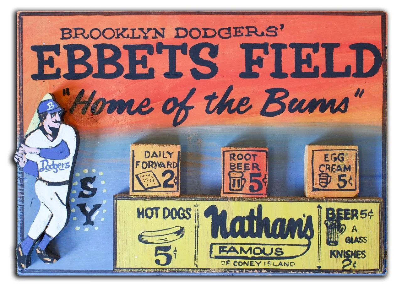 Colorful vintage sign for Ebbet's Field, home of the Brooklyn Dodgers, with prices for daily forward, root beer, egg cream, hot dogs, and beer, and a cartoon baseball player wearing a Dodgers cap.