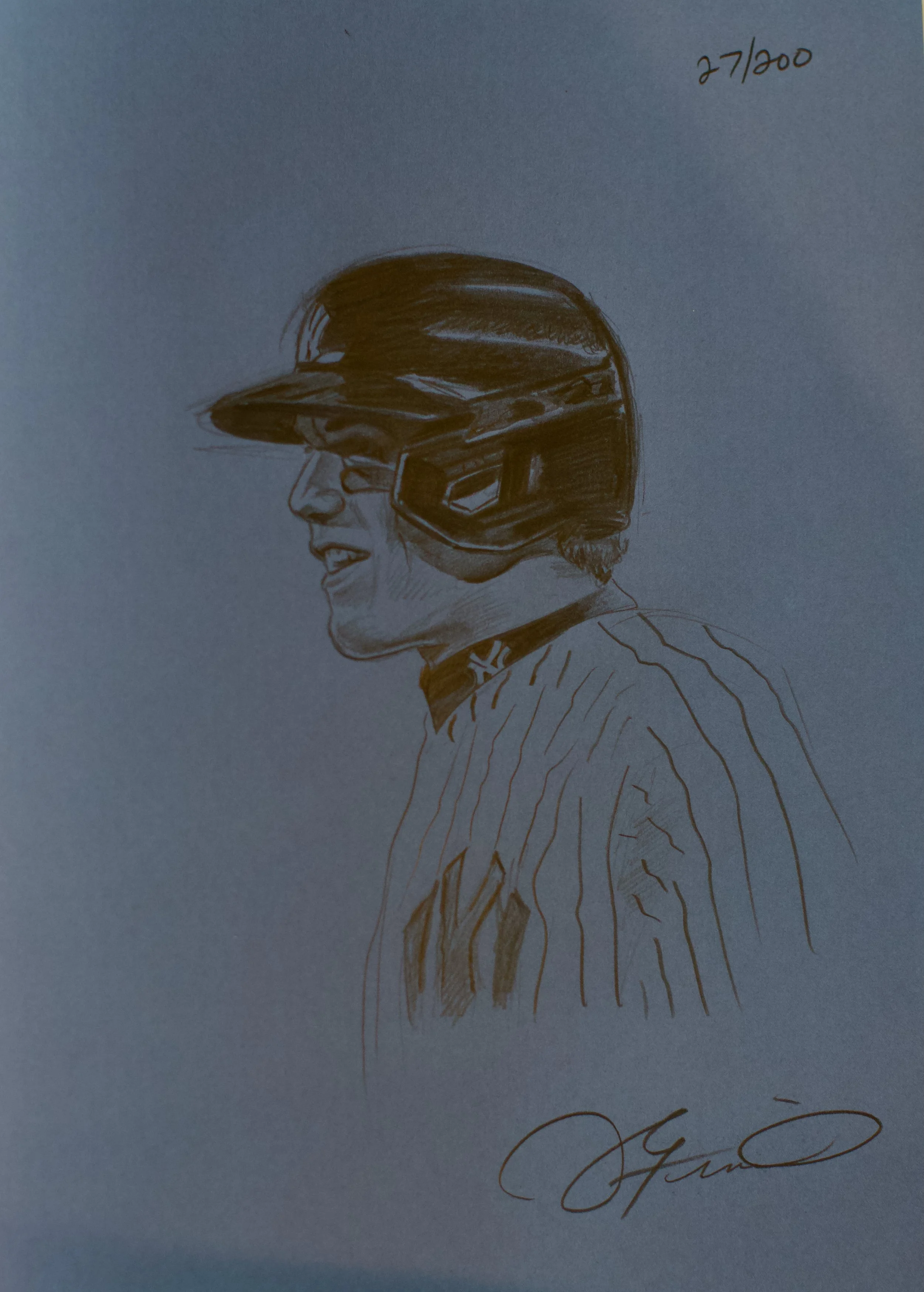 Hand-drawn sketch of a person with glasses and a helmet, smiling in profile, with the number 27/200 written in the top right corner.