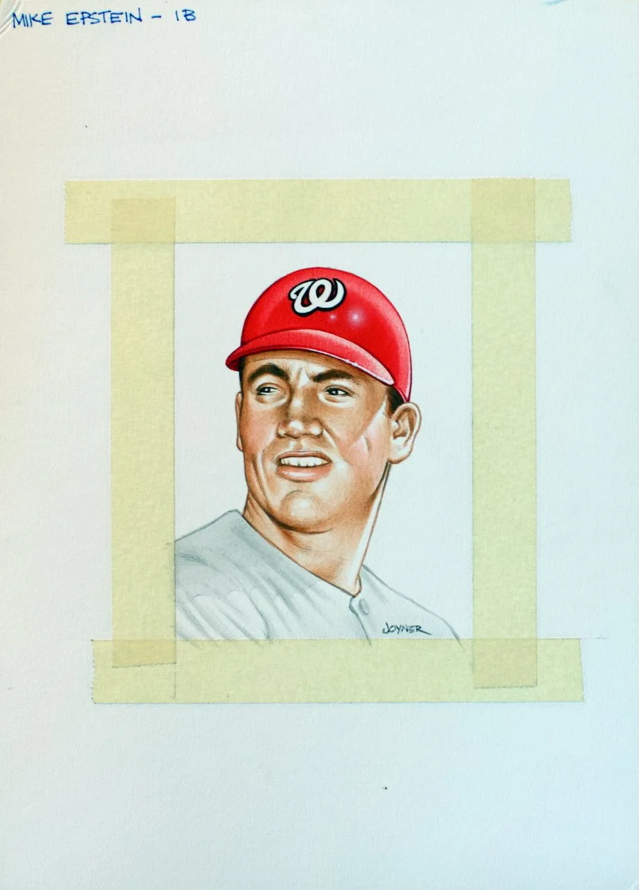 A realistic colored pencil drawing of a man wearing a red Washington Nationals baseball cap with the 'W' logo, looking to the side with a confused or concerned expression, on white paper with the artist's signature at the bottom right corner.