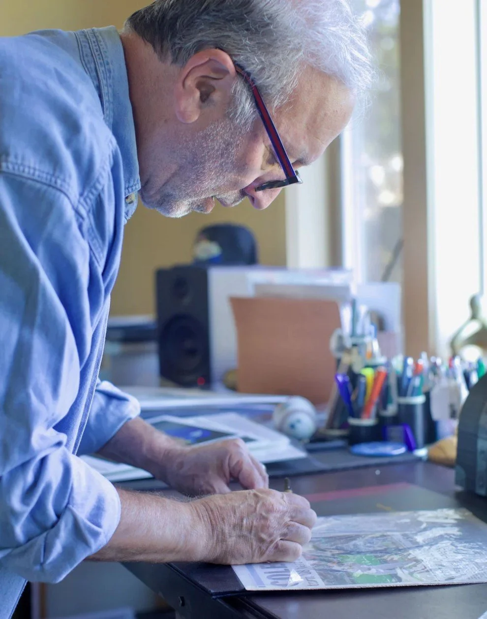 Howard Goldstein working at a desk on artwork from his Jewish baseball collection.