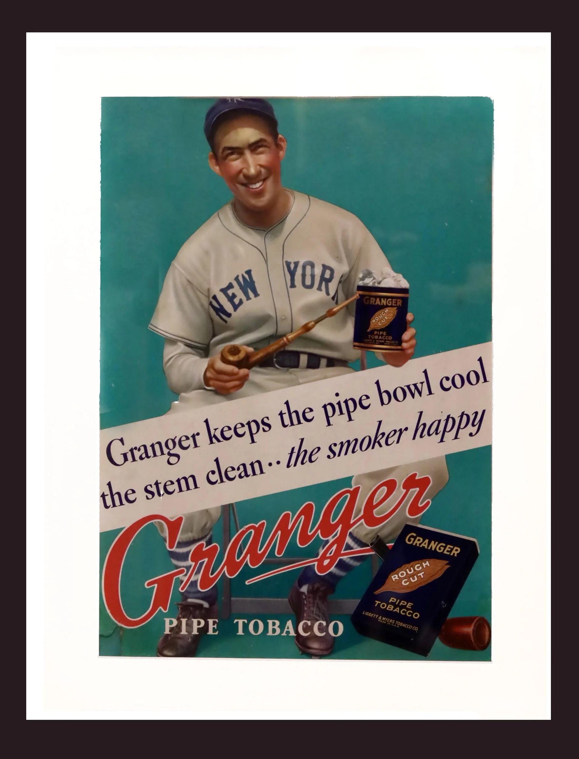 Vintage advertisement featuring a smiling man wearing a New York baseball jersey and a cap. He holds a smoking pipe in one hand and a tin of Granger pipe tobacco in the other. Text on the ad promotes Granger pipe tobacco as keeping the pipe bowl cool and the smoker happy.