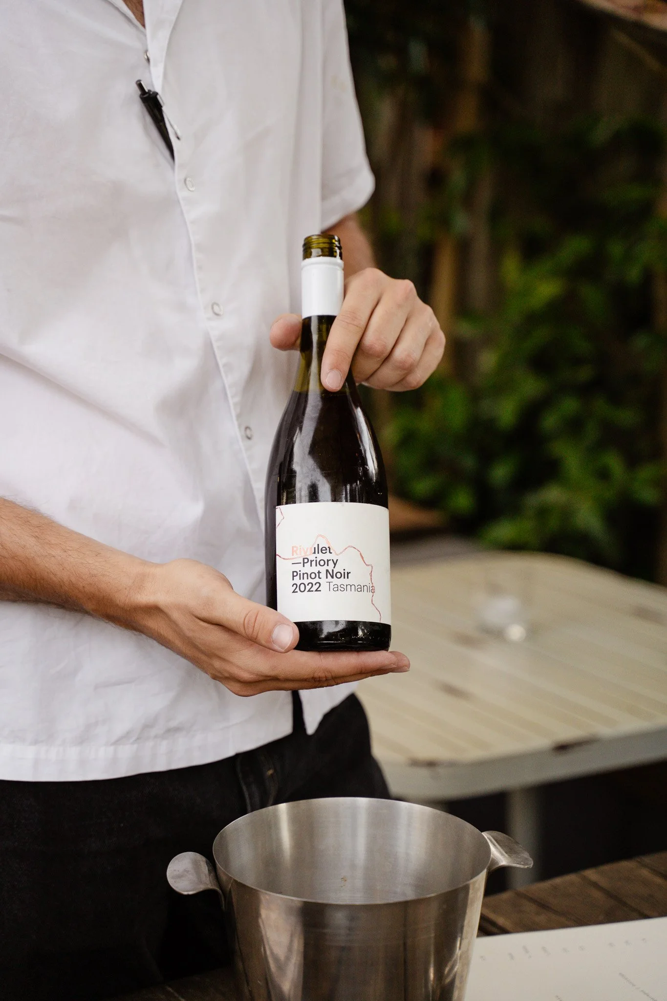 Person holding a bottle of Priory Pinot Noir 2022 wine from Tasmania.