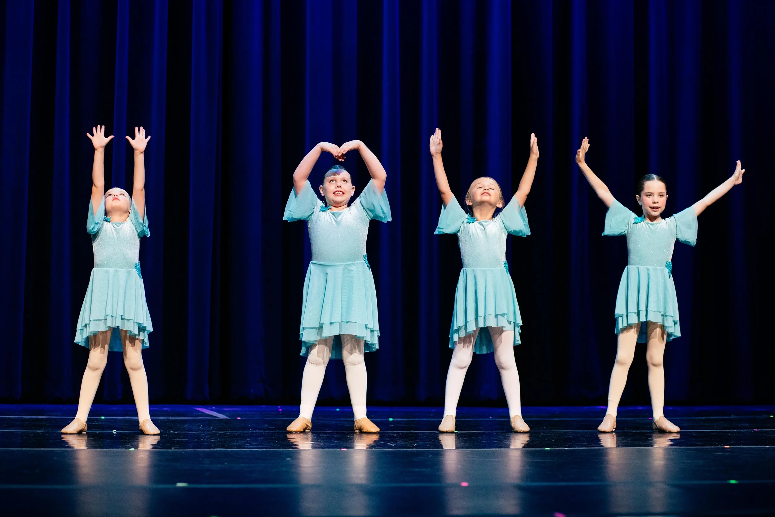 Beginner dance students performing on stage during a Dance Factory East recital.