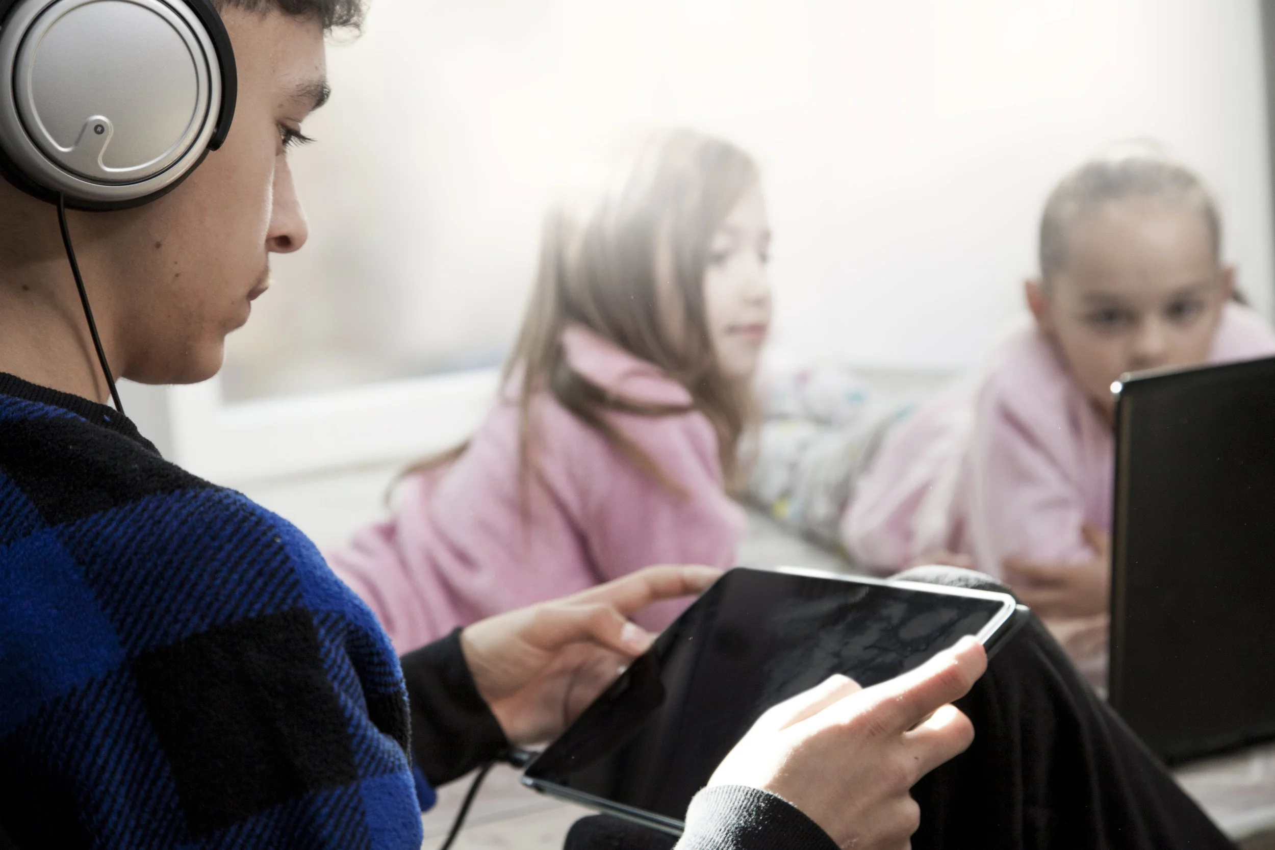 teenager-using-tablet-near-girls-with-laptop.jpg
