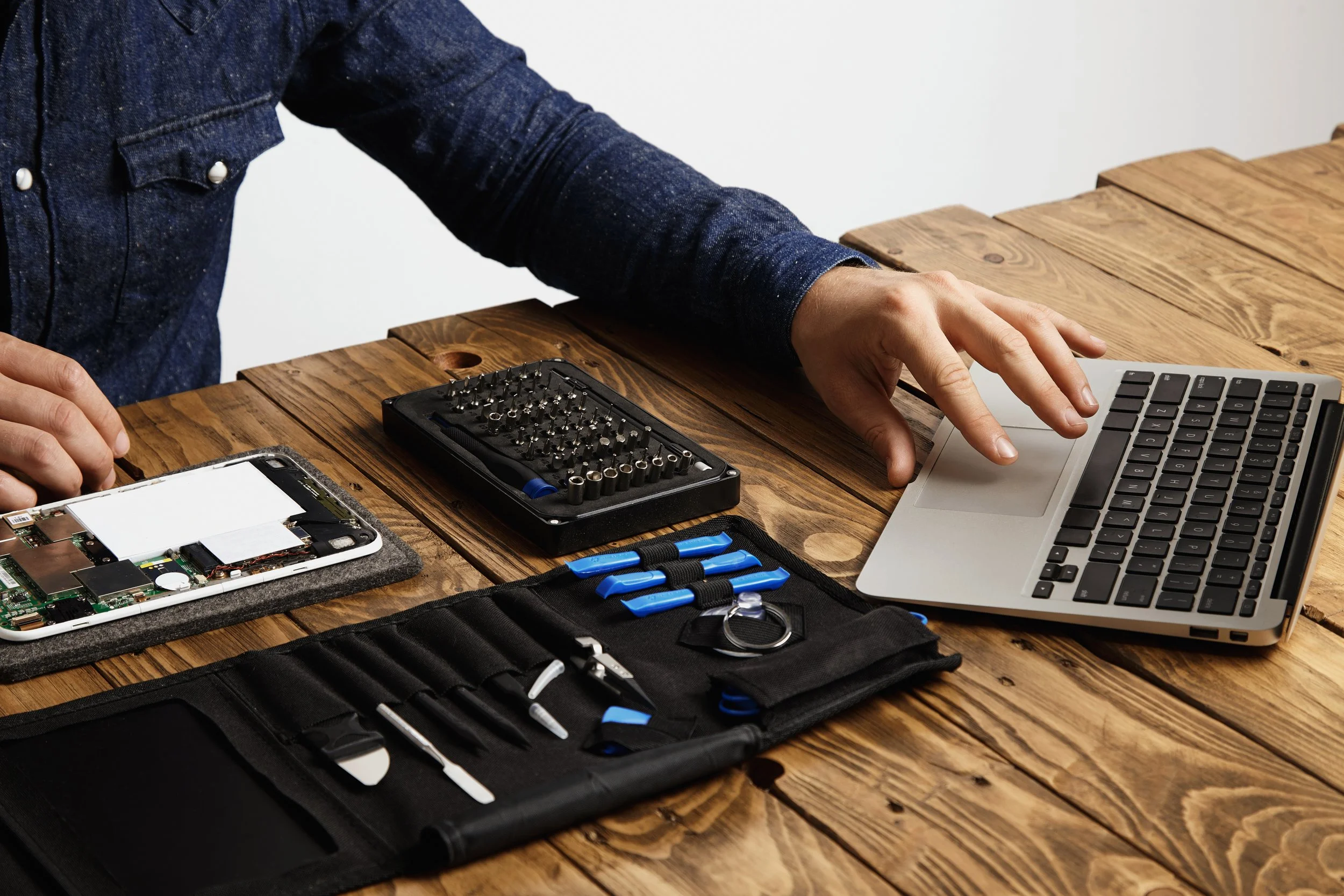 unrecognizable-man-uses-laptop-find-guides-how-repair-electronic-device-tool-bag-broken-gadget-near-vintage-wooden-table.jpg
