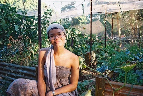 Photo of the author sitting in front of raised garden beds