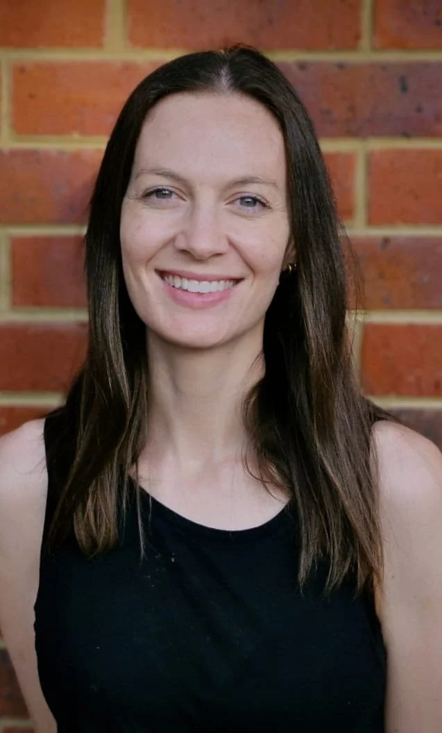 Photo of the author with a black tee shirt in front of a red brick wall