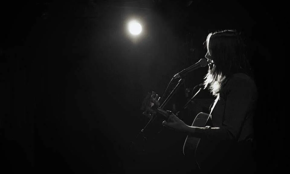 Black and white photo of the author singing and playing guitar
