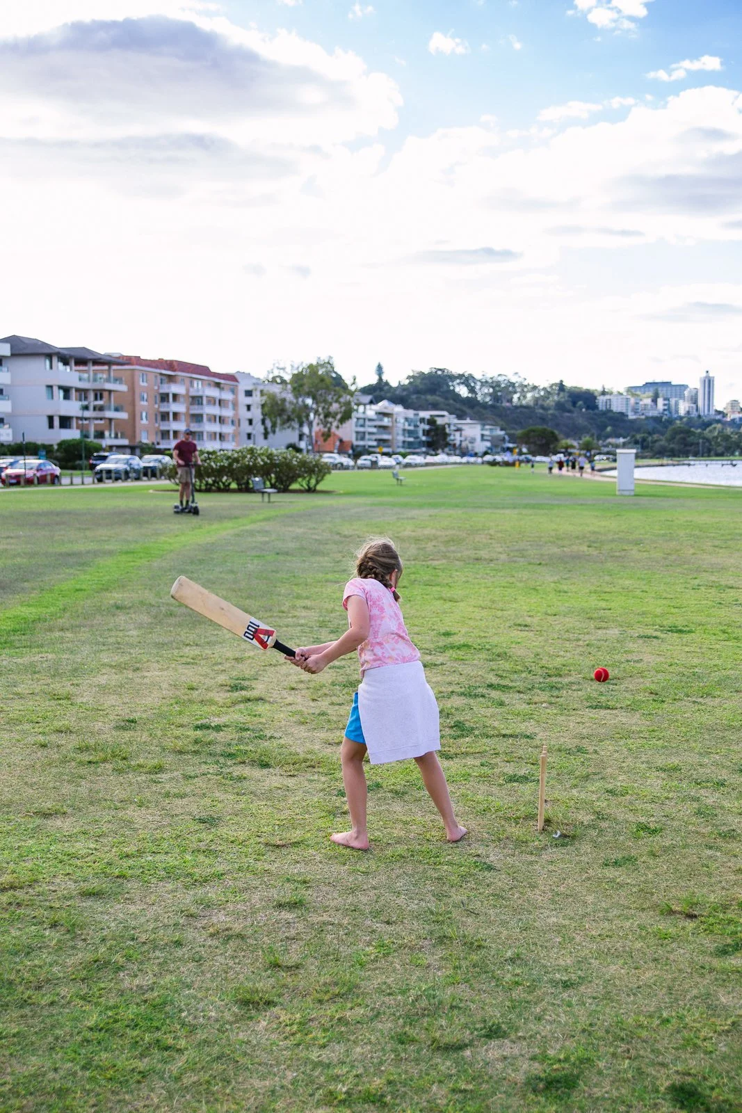 Photo of a young girl on an oval on a sunny day with a cricket bat