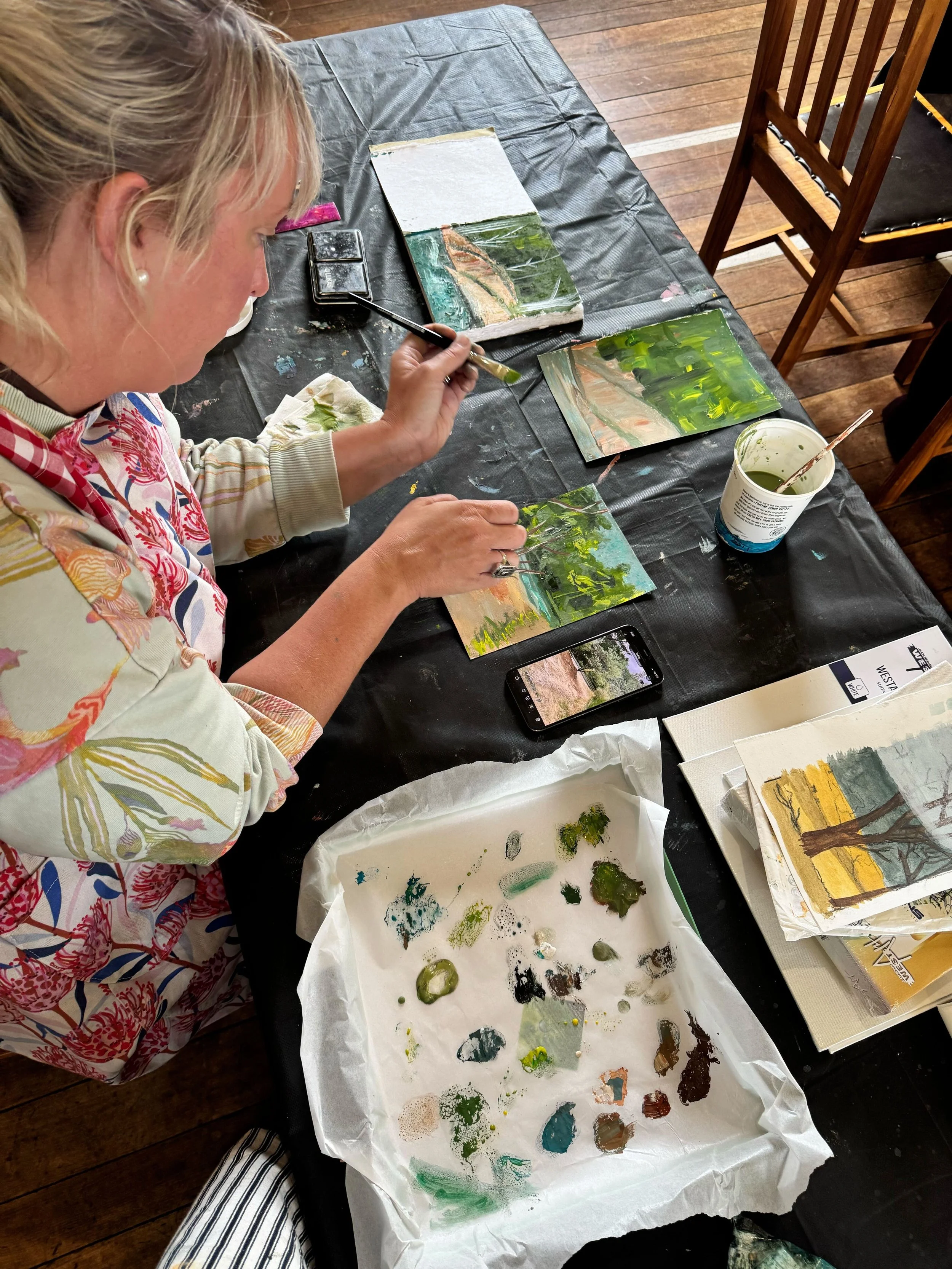 Photo of the author sitting at a table painting with gauche paints
