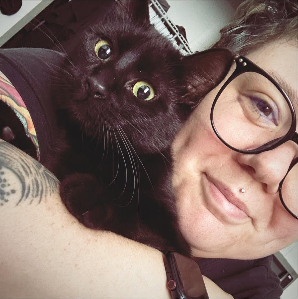 Mary smiling with her black cat Wednesday