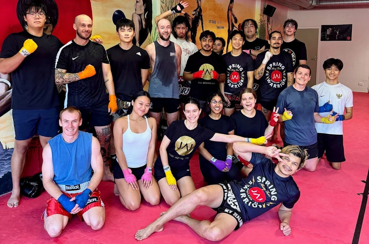 A JAI 101 beginners class at JAI Thai Boxing in Auckland CBD, a mixed group of members of all ages and body types smiling together after training