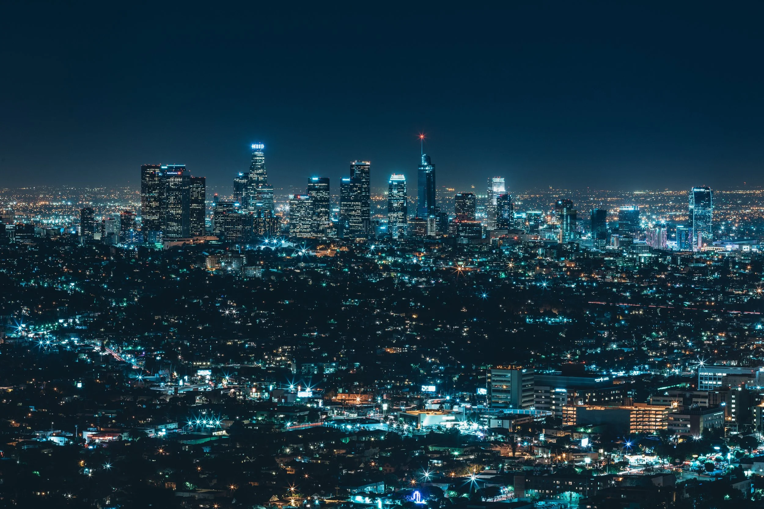 Nighttime view of a city skyline with illuminated skyscrapers and city lights.