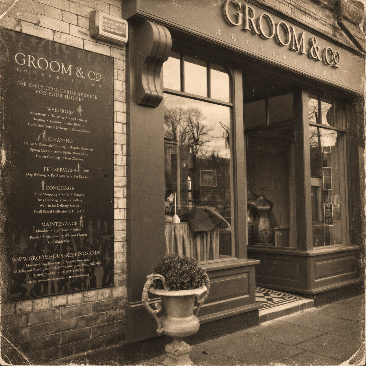 The storefront for Groom & Co Housekeeping, a boutique offering wedding-related services, with a large sign listing their services, a door with large windows, a mannequin inside, and a decorative planter outside.